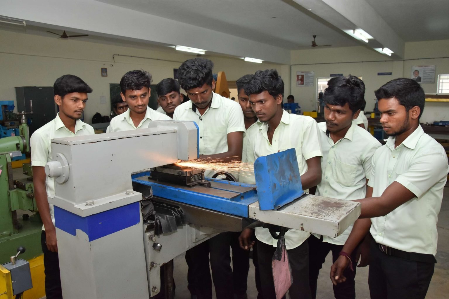 Students working at a surface grinder with sparks